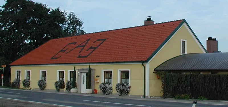 Nachher: dasselbe Gebäude mit neuem rotem Dach und Schanigarten-Überdachung