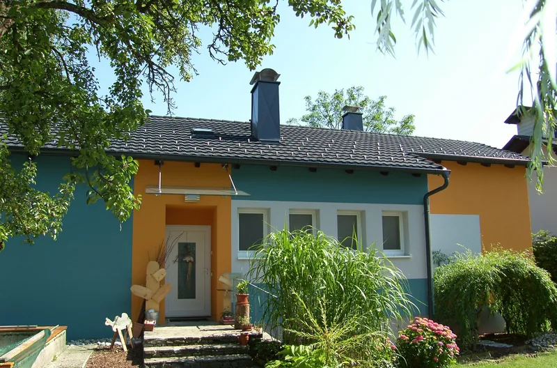 Bungalow mit dunklem Dach, verkleideten Kaminen und bunter Fassade